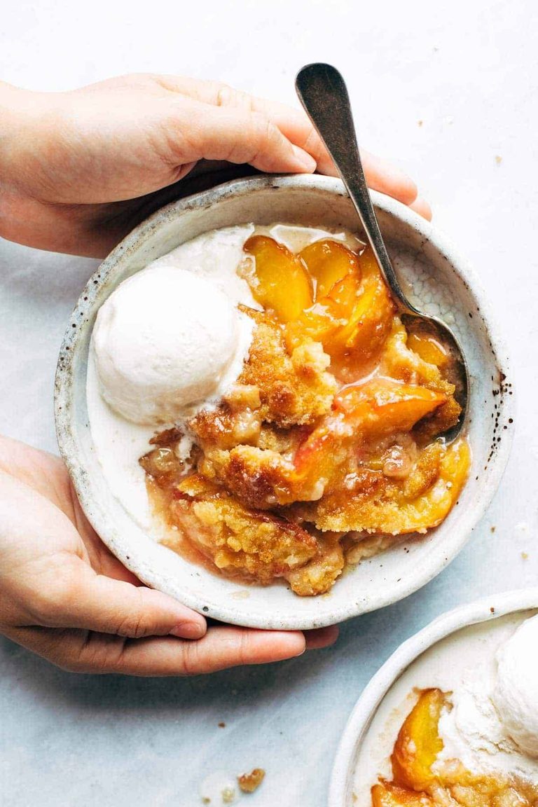 Peach cobbler in a bowl with ice cream.